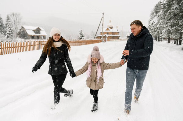 Happy family have fun in winter forest. Mother, father and dauther playing with snow.Enjoying spending time together. Family concept