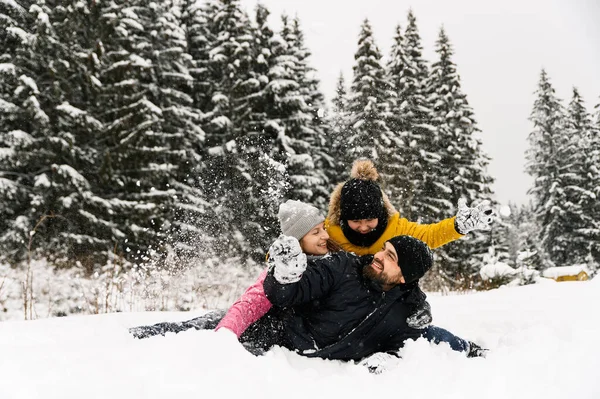 Mutlu aile kış ormanlarında eğlenir ve kameraya bakar. Anne, baba ve oğul karla oynuyor. Aile Noel konsepti. Birlikte vakit geçirmekten zevk alıyorum.