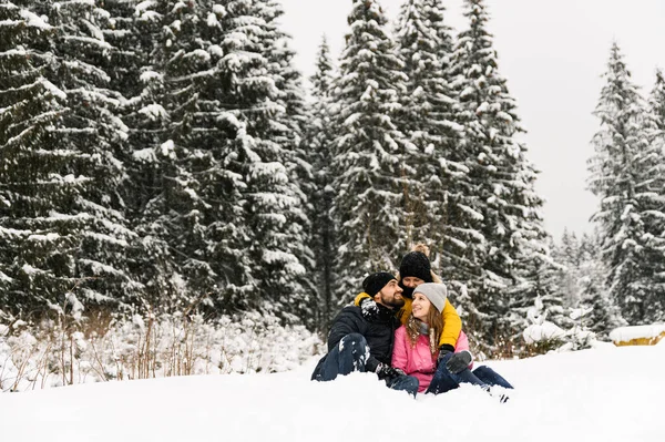 Mutlu aile kış ormanlarında eğlenir ve kameraya bakar. Anne, baba ve oğul karla oynuyor. Aile Noel konsepti. Birlikte vakit geçirmekten zevk alıyorum.