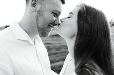 Yüzlerinde gülümsemeyle yüz yüze duran genç bir çiftin yakın çekimi. Bir kızla mutlu bir adam. Aşıkların portresi