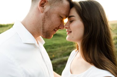 Yüzlerinde gülümsemeyle yüz yüze duran genç bir çiftin yakın çekimi. Bir kızla mutlu bir adam. Aşıkların portresi