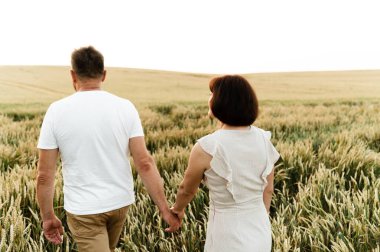 Erkek ve kadın sahadayken sarılıyor. Gün batımında orta yaşlı bir çiftin yürüyüşü. Orta yaşlı bir karısı olan bir koca. Ebeveynlerin portresi