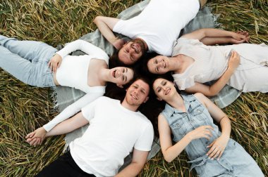 Bir grup insan zemin üzerinde yatıyordu. Orta yaşlı bir aile doğada birlikte dinleniyor. Farklı milletlerden mutlu bir grup insan. Gülen insanlar. aile pikniği