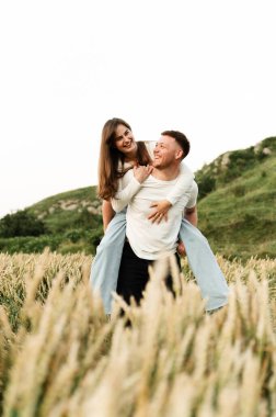 Buğday tarlasında oynayıp gülen aşıklar. Modern bir çiftin romantik ilişkisi. Aşıklar doğada yürür.