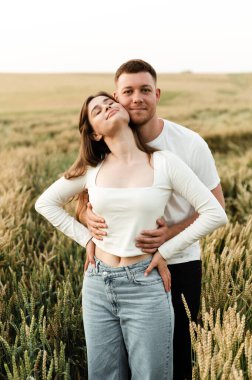 Genç bir adam ve bir kız güzel bir gün batımında yürüyorlar. buğday tarlasında çift