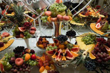 Üzerinde çeşitli egzotik meyve ve şekerlerin olduğu düğün meyve masası. Meyveli çikolata. Ziyafette armut, elma, ananas ve daha bir sürü yiyecek.