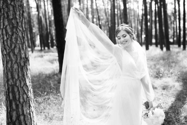 かわいい花嫁が森の中の屋外にいるウェディングドレスで回転しています — ストック写真
