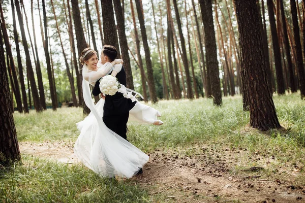 新郎は花嫁を抱きしめる 若い夫婦の結婚式の日 恋人が森の中を歩く — ストック写真