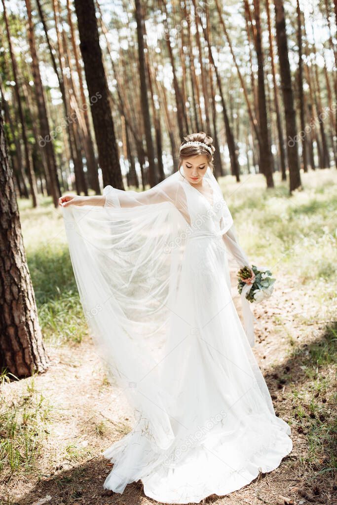 a cute bride is spinning in a wedding dress being outdoors in the forest.