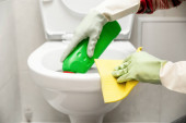 a WC-hez közeli kezek tisztítása rongy és tisztítószer tartásával a tisztításhoz