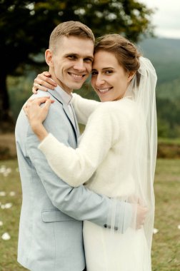 Genç düğün çifti dağlardaki düğün töreninden sonra nazikçe sarılıyor. Güzel düğün günü