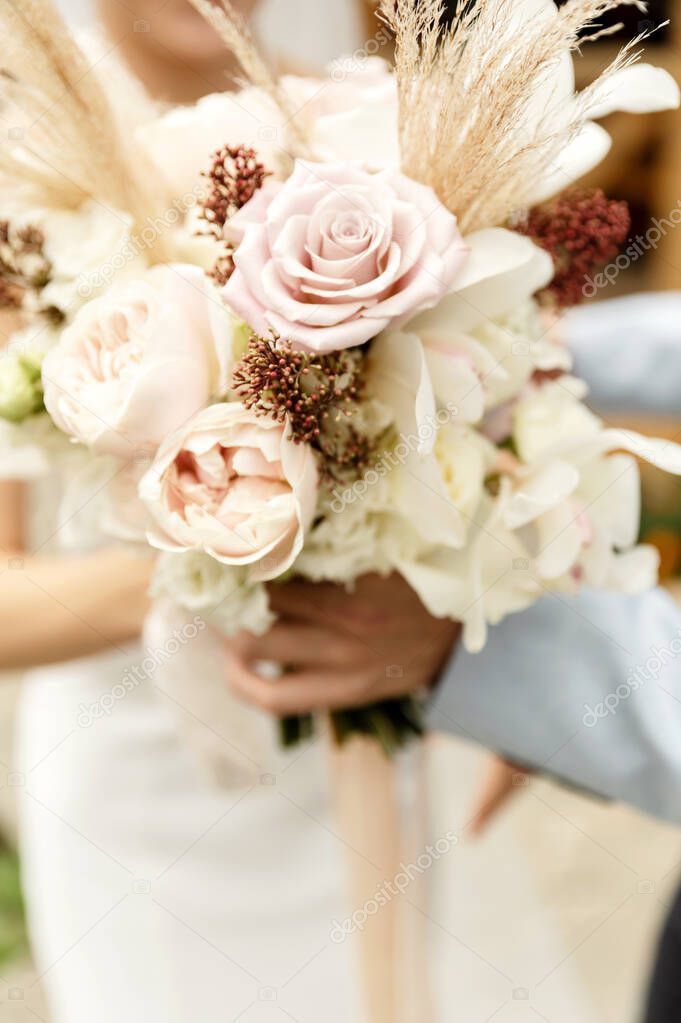 the bride's bouquet stands next to other wedding accessories on a beautiful background.stylish bouquet with dried flowers