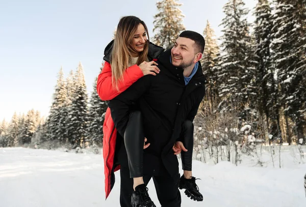 Aşk ve tatil kavramı. Mutlu çift kışın dışarıda sarılıp gülüyor. Doğada bir çift.
