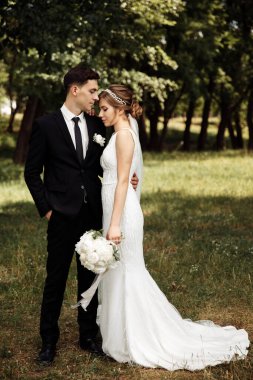 Genç çift gelin ve damat ormanda yürüyüşe çıktılar. Düğün günü konsepti. Romantik gün. Yeni evli çiftin portresi.