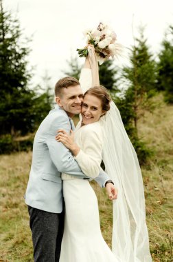 Güzel, mutlu, aşık genç bir çift güzel bir manzaranın arka planında, dağlarda birbirlerine sarılıyorlar. düğün günü anı