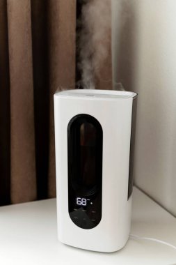 Hava nemlendirici yatağın yanındaki komodinin üzerindeki odada. Kablosuz ağ ve uzaktan kumandalı akıllı nemlendirici. elektronik kontrol paneli.