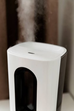 Hava nemlendirici yatağın yanındaki komodinin üzerindeki odada. Kablosuz ağ ve uzaktan kumandalı akıllı nemlendirici. elektronik kontrol paneli.