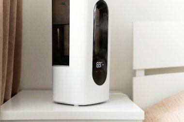 Hava nemlendirici yatağın yanındaki komodinin üzerindeki odada. Kablosuz ağ ve uzaktan kumandalı akıllı nemlendirici. elektronik kontrol paneli.