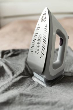 Kıyafetleri ekolojik modda ütülemek için akıllı buhar jeneratörü. Ev işi konsepti. Modern demir yatağın üstünde..