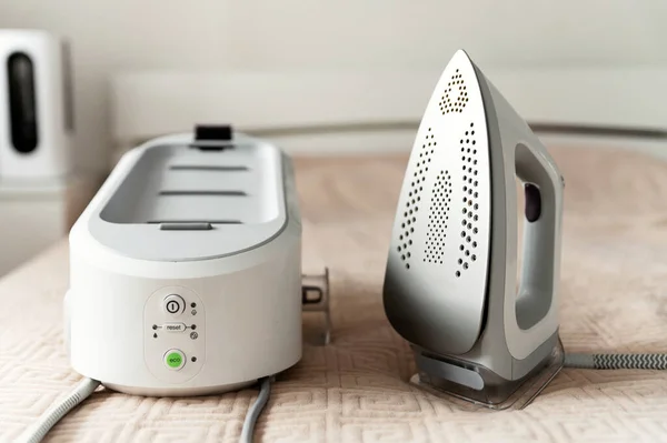 smart steam generator for ironing clothes with ecological mode. housework concept. the modern iron is on the bed.