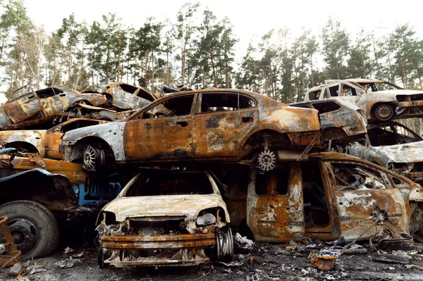 Paslı, yanmış arabalar roket patlamalarıyla yok edildi. Bomba parçaları parçalanmış arabalar. Ukrayna 'da Rus vandalizmi. Ukrayna 'da savaş. Kyiv, Bucha ve Irpen 'de tahrip edilen arabalar.