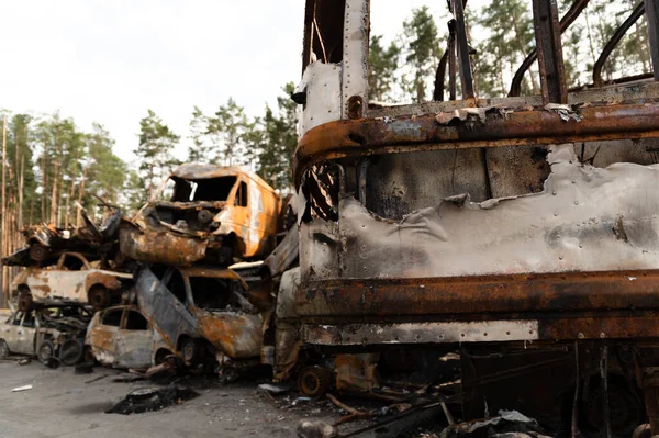 Ukraynalı adam Rus füzelerinden etkilenen kırık ve yanmış arabaların arka planında duruyor. Arabaları boşaltın. Adam bozuk arabalara bakıyor. Bomba parçaları delikleri. Ukrayna 'da savaş