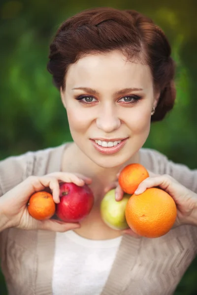 Beautiful woman with spring fruits resting on nature outdoors. Happy girl relaxing in summer park — Stock Photo, Image