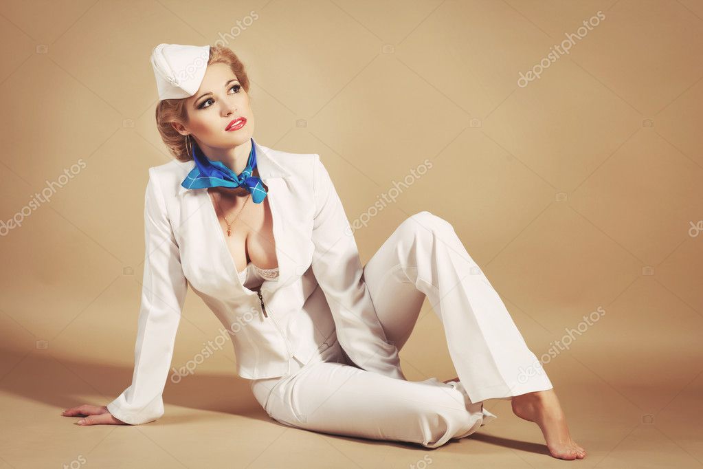 Beautiful Blonde Woman Stewardess Or Sailor In Marine Concept And Pinup Style American Sexy Girl In Flight Attendant White Costume Smiling With Bright Makeup And Hairstyle Happy Air Hostess In Studio
