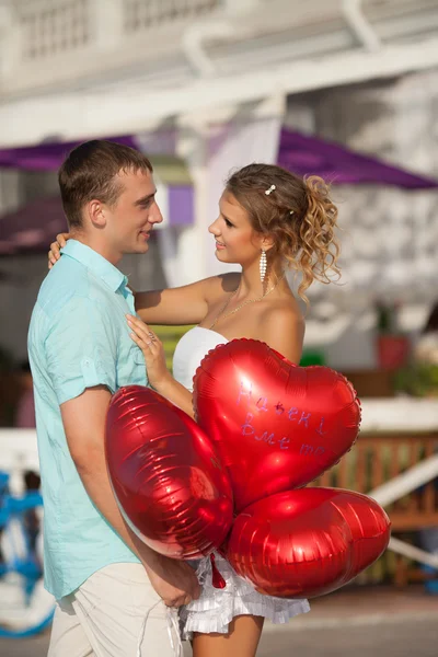 Couple adolescent embrassant sur sortir ensemble avec un tas de cœurs de ballons . — Photo