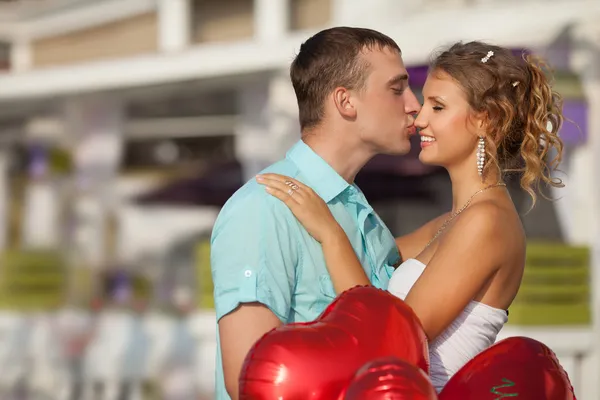 Adolescente pareja abrazando en citas con montón de globos corazones . — Foto de Stock