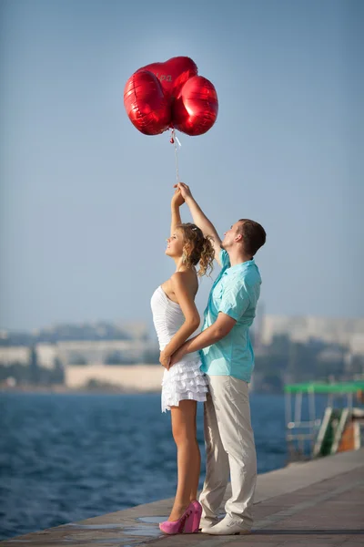 Teenage paar omarmen op dating met bos van ballonnen harten. — Stockfoto
