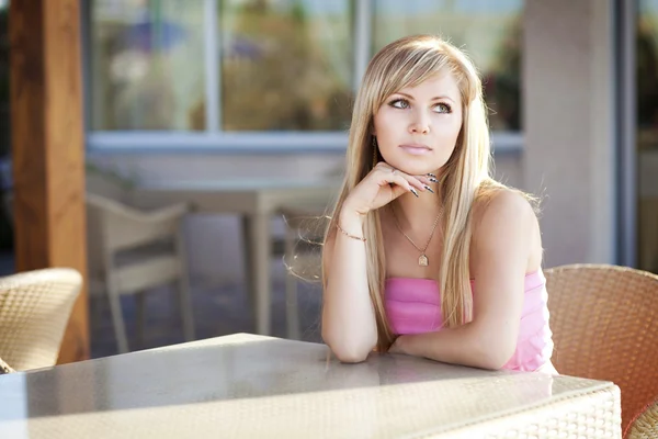 Красивая блондинка сидит на улице и думает: — стоковое фото