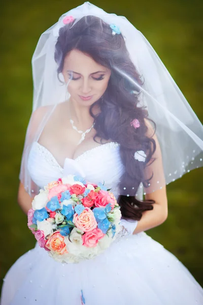 Glückliche Braut in Schleier hält Brautstrauß — Stockfoto