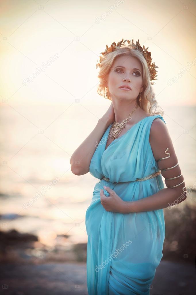 Woman in Greek style on sunset near ancient ruins.