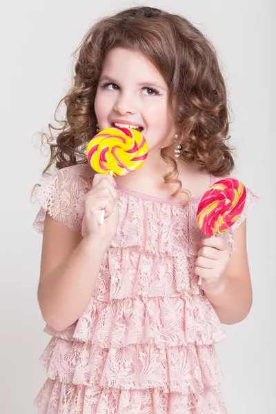 Bambino divertente con caramelle lecca-lecca, bambina felice mangiare grande lecca-lecca di zucchero, bambino mangiare dolci. bambino sorpreso con caramelle . — Foto Stock