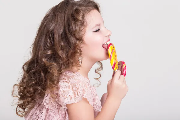 Morsomt barn med godteri kjærlighet på pinne, glad liten jente som spiser stor sukkerbit, barn som spiser godteri. overrasket barn med godteri . – stockfoto