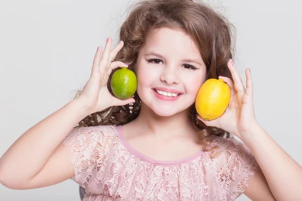 Cute little girl with lemons and lime — Stock Photo, Image