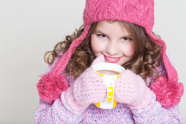 Beautiful child in winter hat drinking hot chocolate, little girl in woolen accessories with cup of tea or cocoa. — Stock Photo, Image