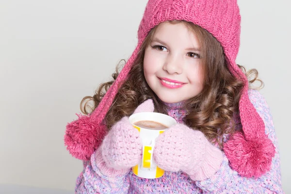 Belle enfant en chapeau d'hiver buvant du chocolat chaud, petite fille en accessoires de laine avec tasse de thé ou de cacao . — Photo