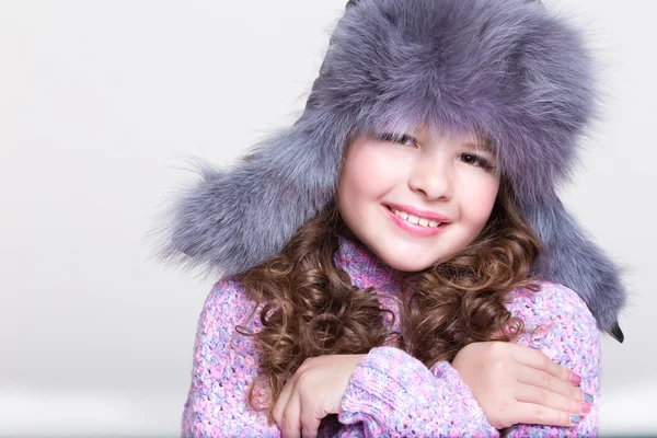 Lovely little girl in winter fur hat and colorful cozy sweater. — Stock Photo, Image