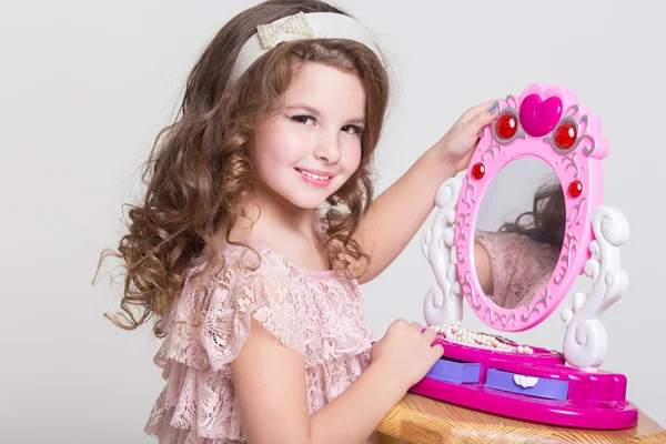 Χαριτωμένο μικρό κορίτσι με το παιχνίδι του καθρέφτη και κραγιόν. — Φωτογραφία Αρχείου