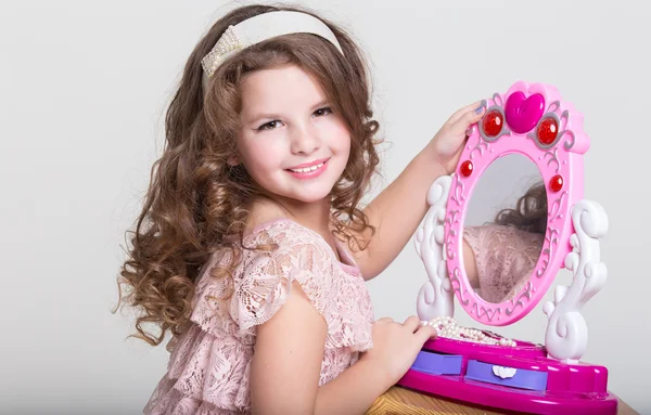 Cute little girl with toy mirror and lipstick. — Stock Photo, Image