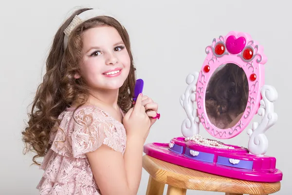 Petite fille mignonne avec miroir jouet et rouge à lèvres . — Photo