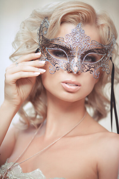 Vogue style portrait of beautiful delicate woman in venetian mask and fashionable dress.