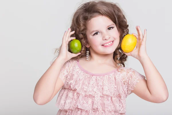 Χαριτωμένο μικρό κορίτσι με τα λεμόνια και λάιμ Royalty Free Εικόνες Αρχείου
