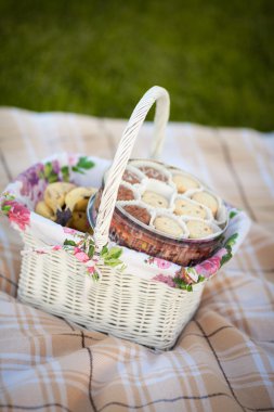 Cookies in picnic basket on green lawn clipart