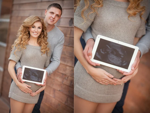 Pregnant woman with husband holding ultrasound scan on her tummy — Stock Photo, Image