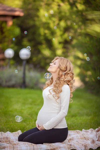 Young pregnant woman relaxing in park outdoors — Stock Photo, Image