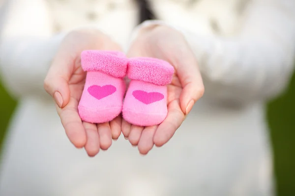 Femme enceinte ventre tenant chaussons bébé rose — Photo