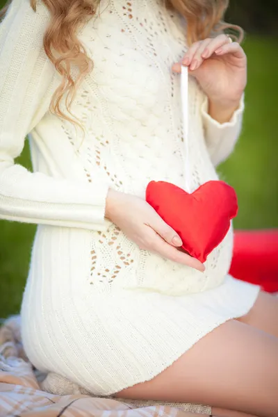 Pregnant woman belly holding pink baby booties — Stock Photo, Image